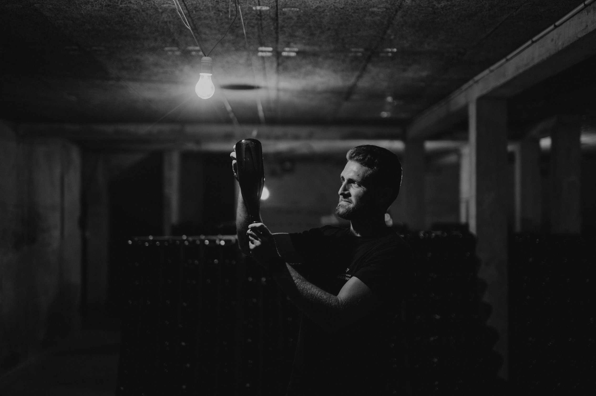 Victor Couvreur vérifie la clarté de son vin en fin de remuage ! Bouteille sur pointe dans la cave du domaine Couvreur-Fondeur.