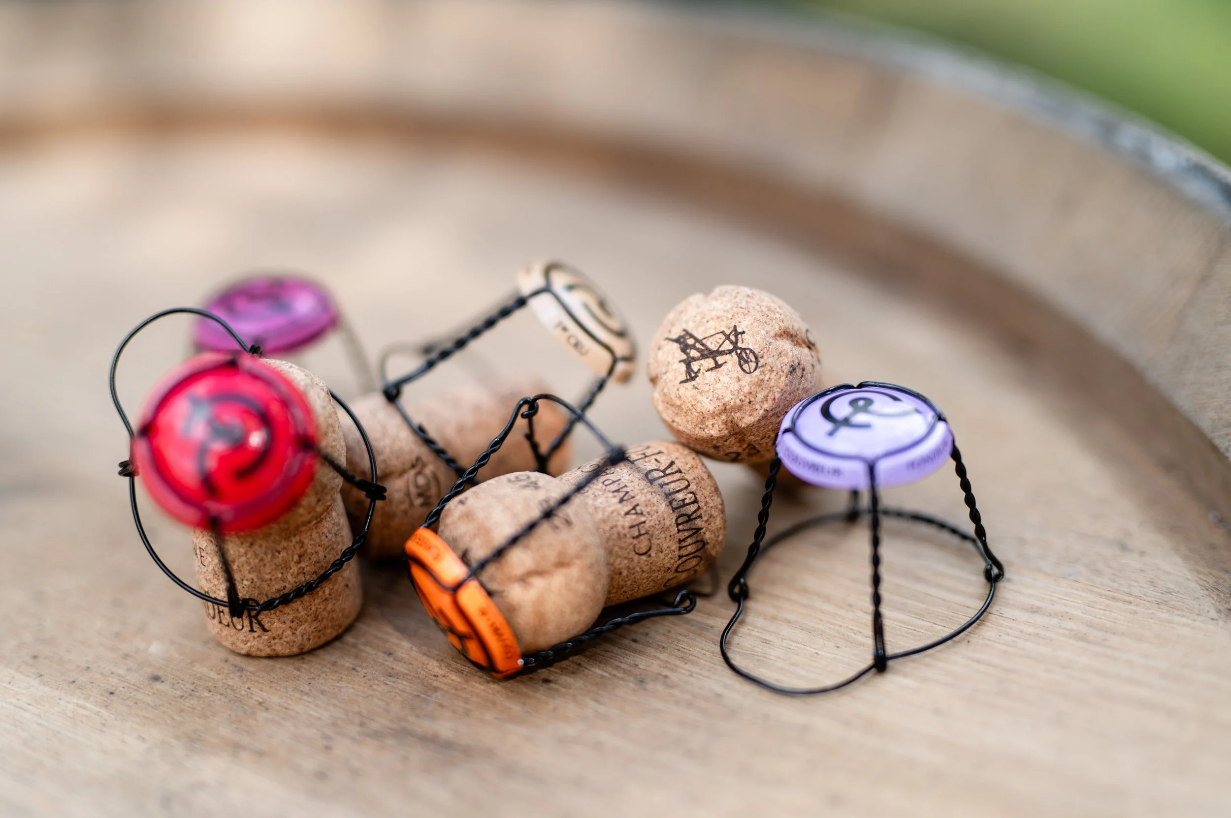 Bouchons de vin encadrés par des fils, certains avec étiquettes en plastique colorées, placés sur une surface en bois.