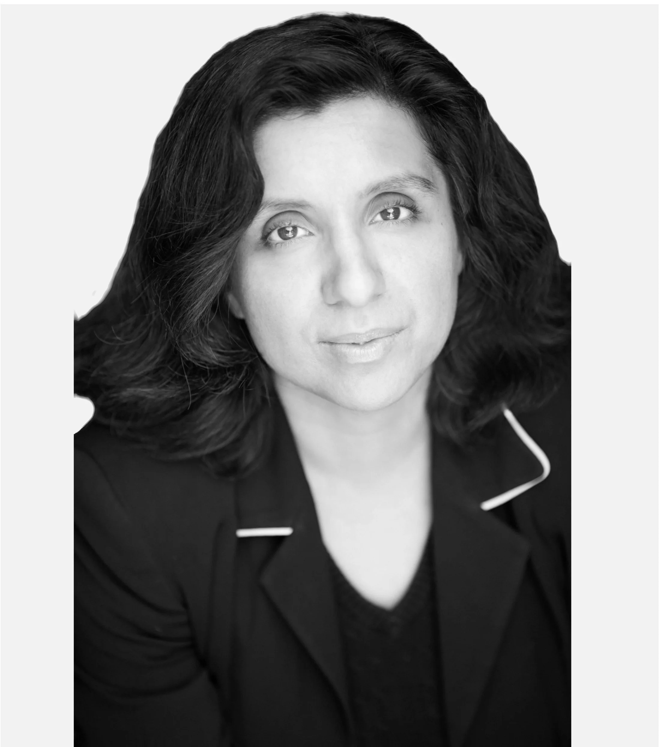Black and white portrait of a person with medium-length dark hair, wearing a black blazer with white piping.