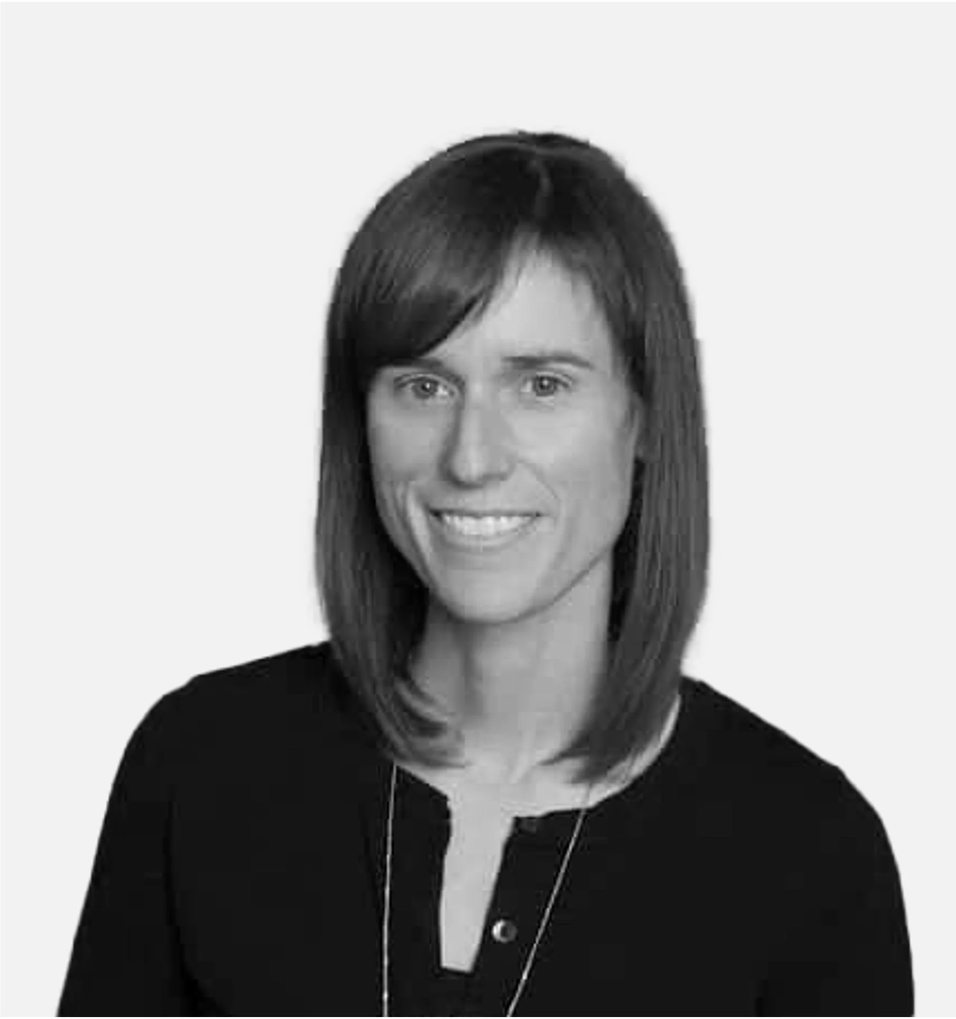Black and white portrait of a smiling person with shoulder-length hair wearing a dark top.