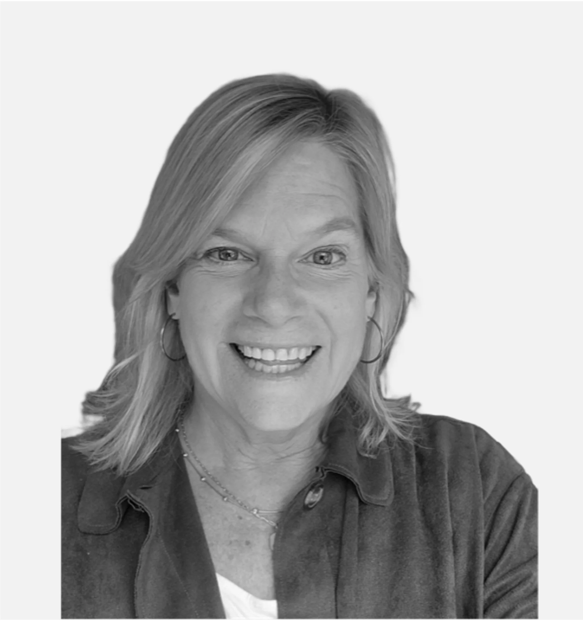 Black and white photo of a smiling person with shoulder-length hair and hoop earrings.