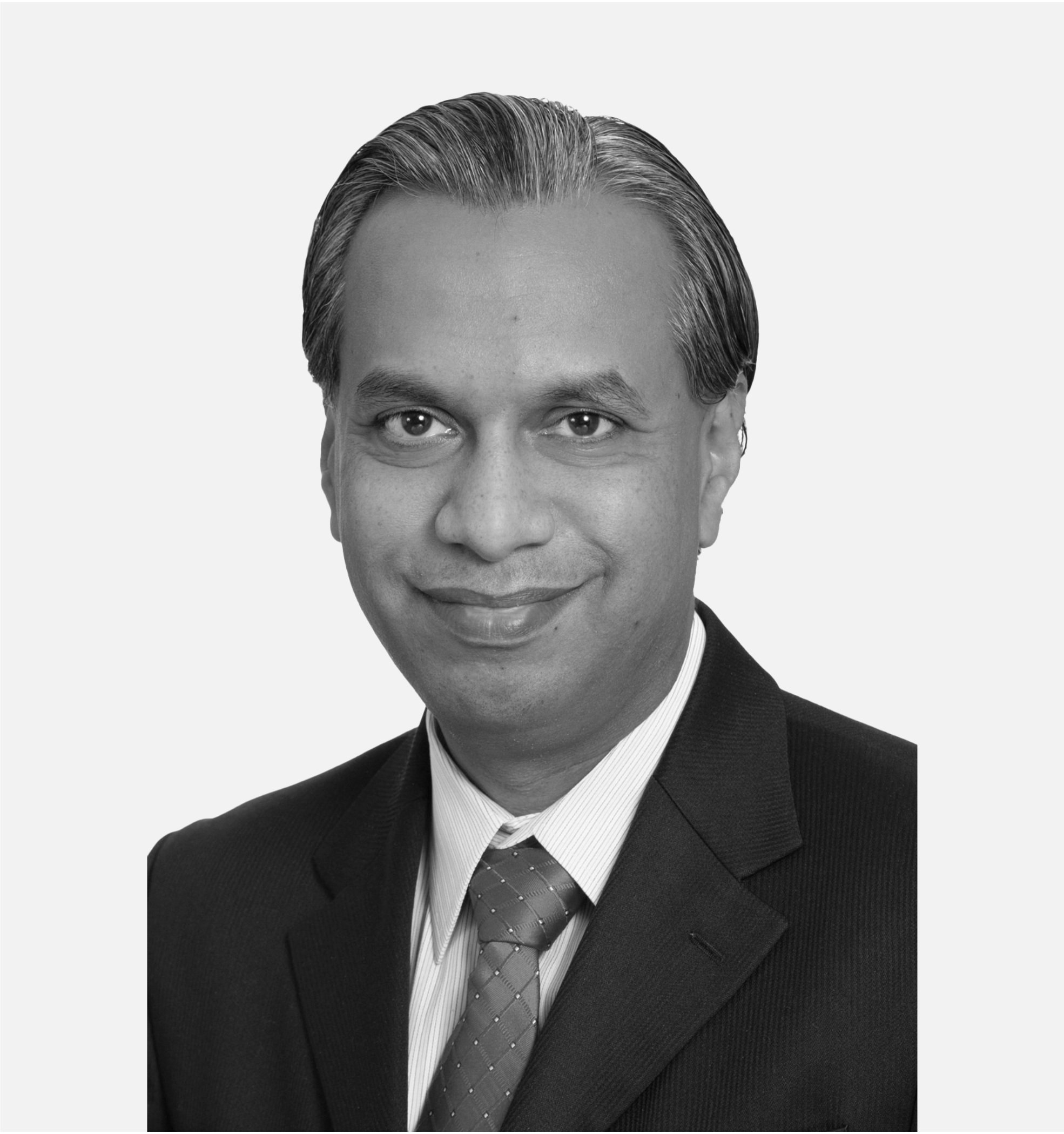 Professional headshot of a man in a suit and tie, smiling, black and white.