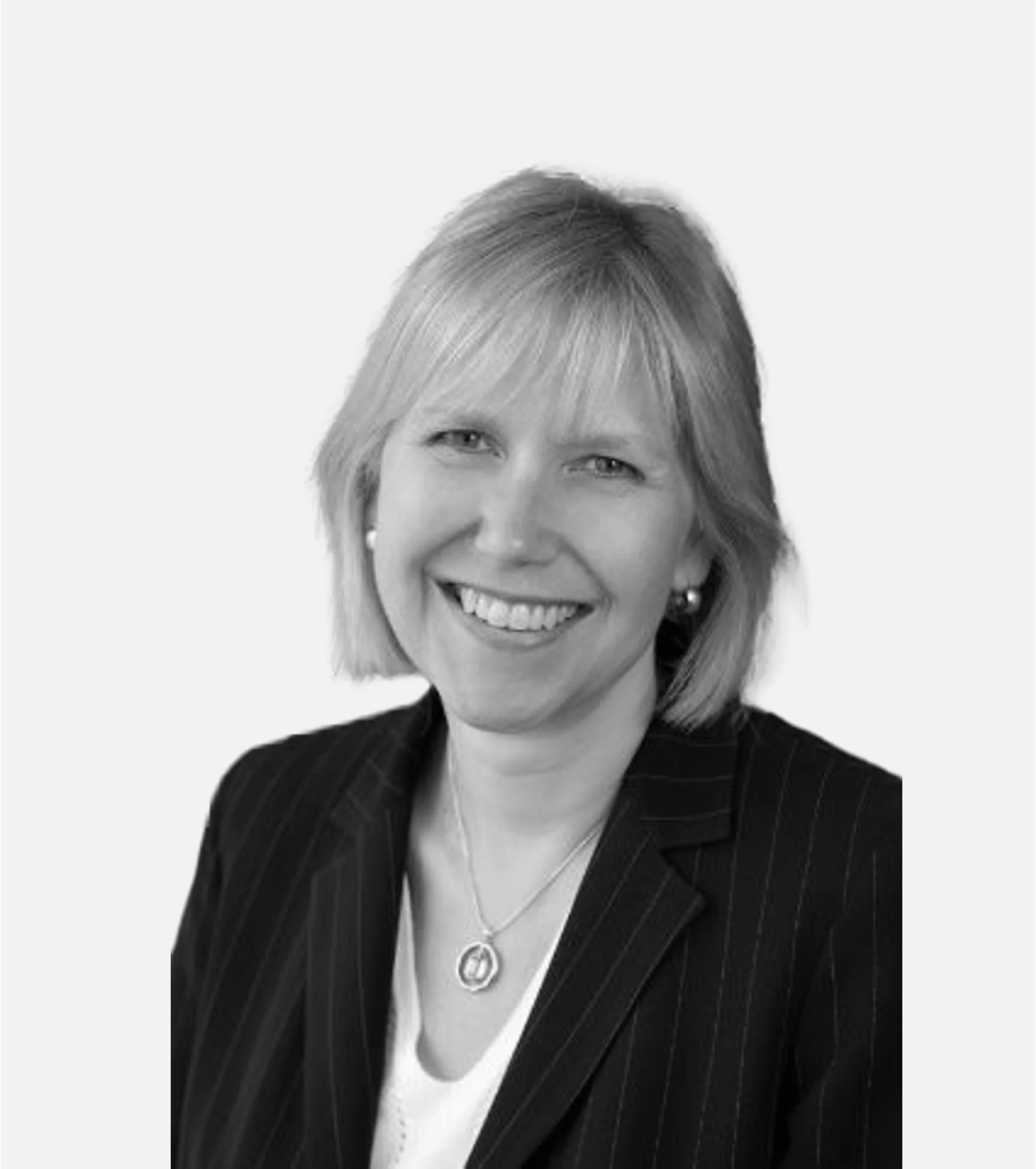 Smiling woman in a pinstripe blazer and white top, wearing a necklace and earrings, with shoulder-length light hair.