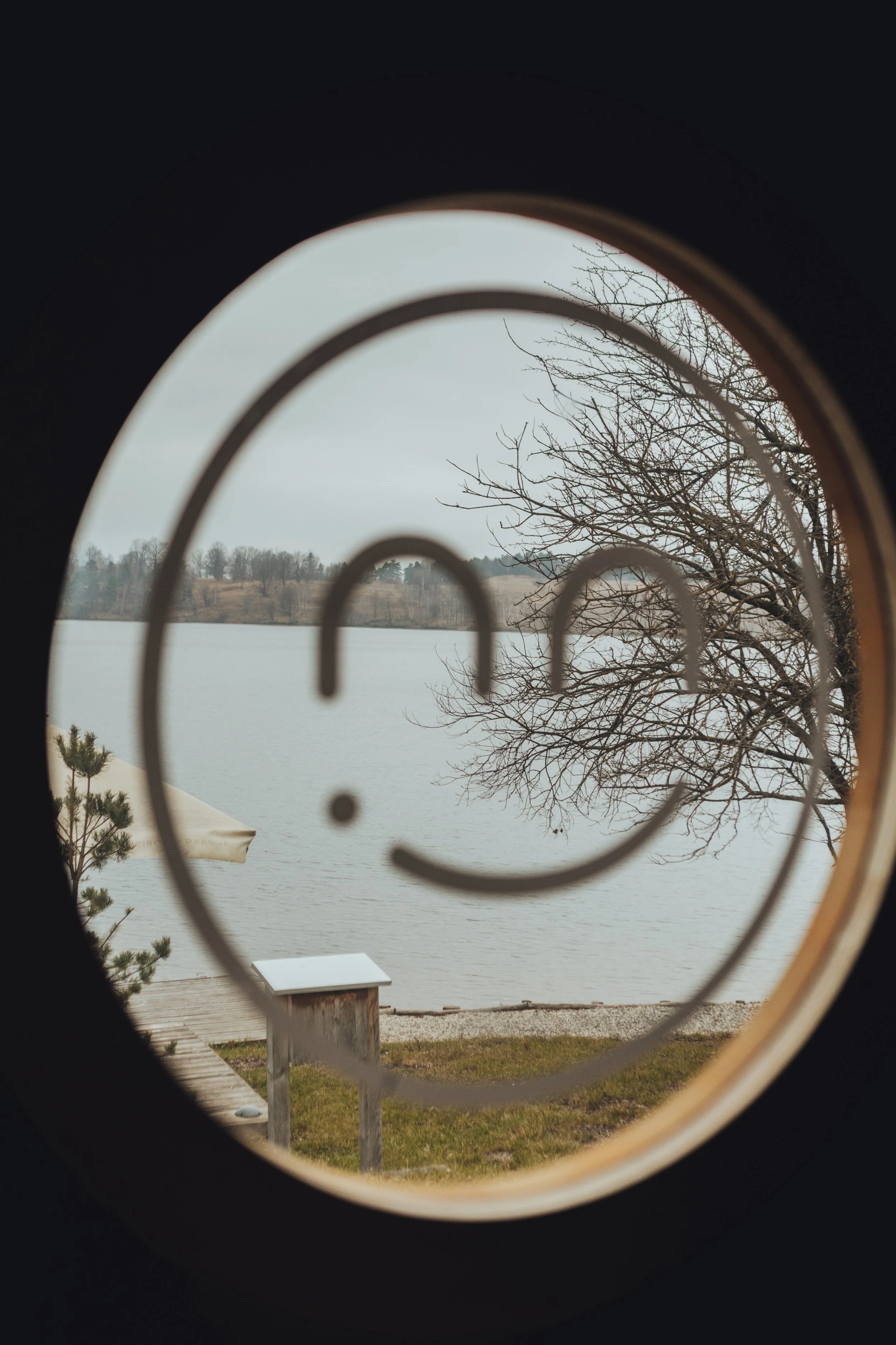 View of a lake and trees through a round window.