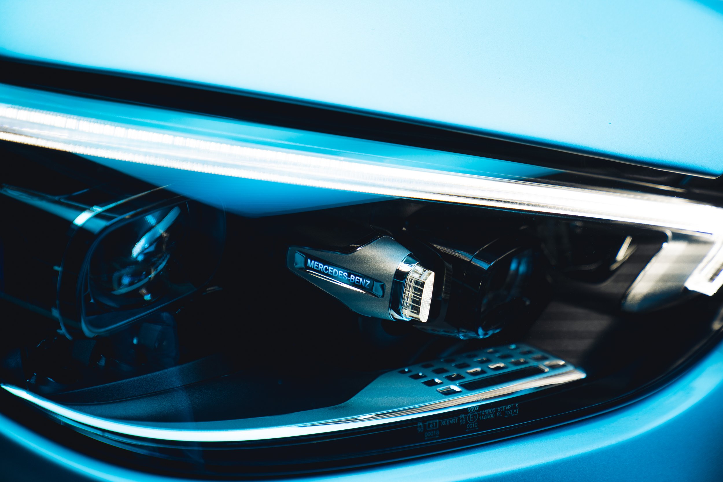Close-up of a Mercedes-Benz car headlight with blue and black interior elements.