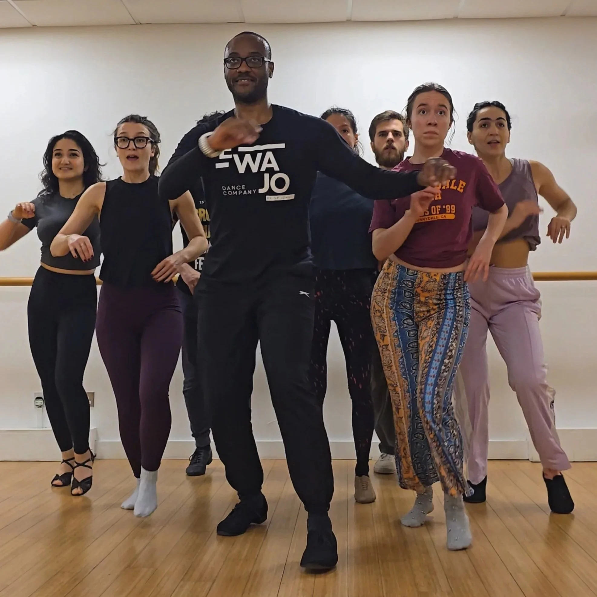 Two dancers performing on stage with colorful lighting, wearing stylish costumes and sunglasses, dancing energetically. Salsa dancers.