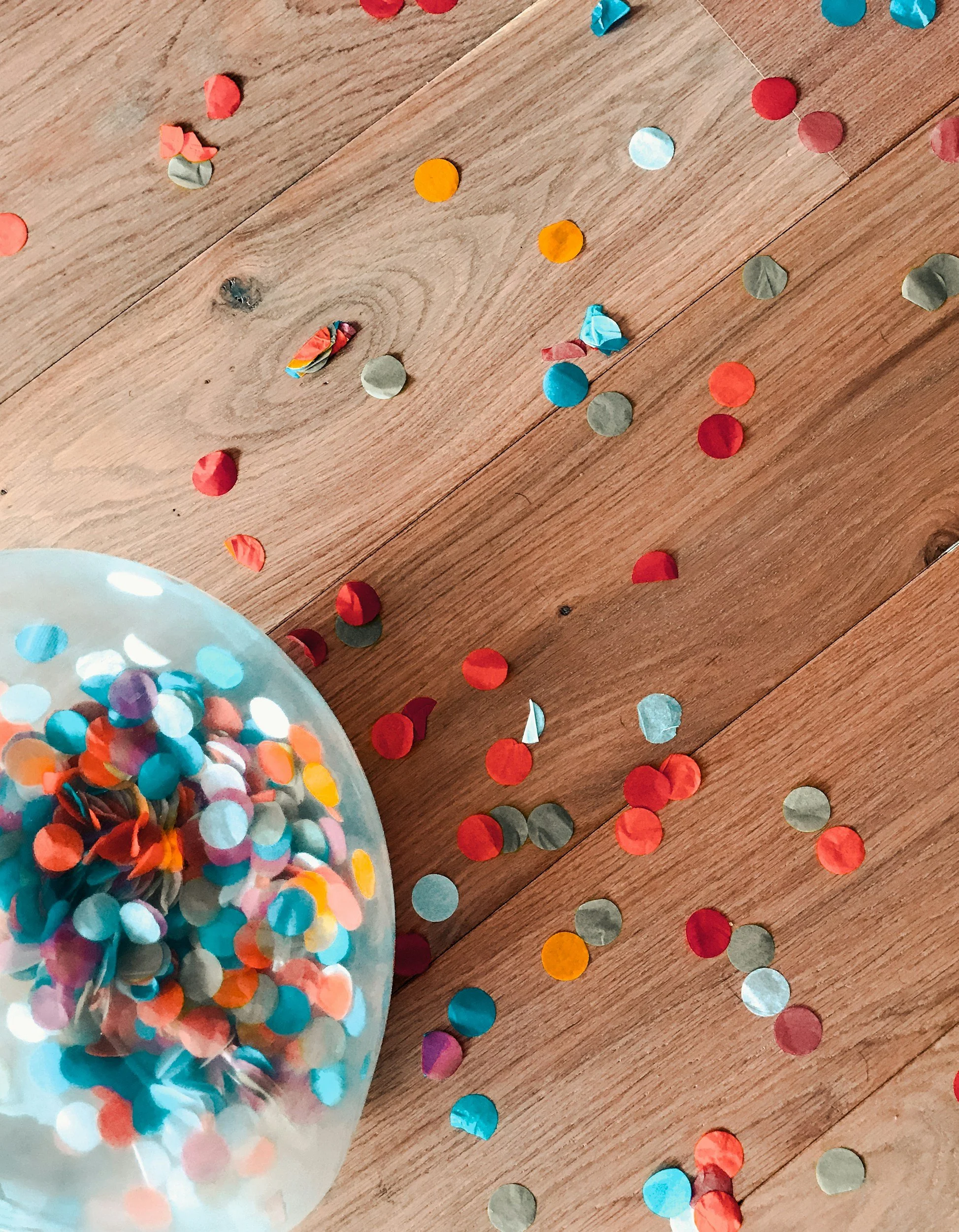 Balloon with colorful confetti inside lying on a table next to more confetti
