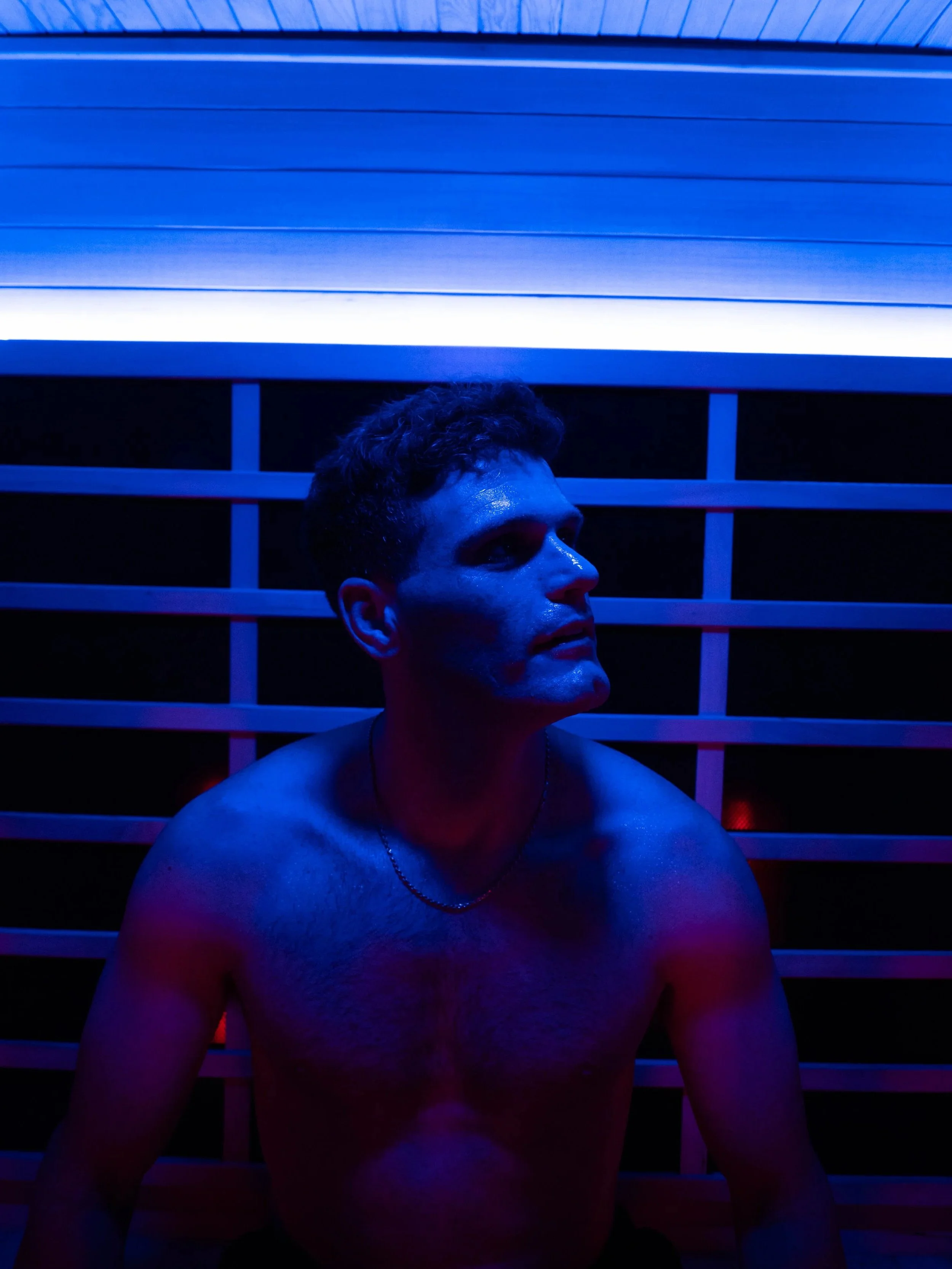 Guest seated in a SOLiX infrared sauna with blue chromotherapy lighting