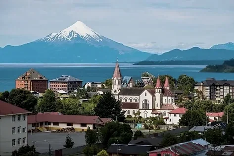 Paisaje urbano de Puerto Varas con montañas y volcán Osorno en el fondo, ciudad con iglesias y edificios en primer plano