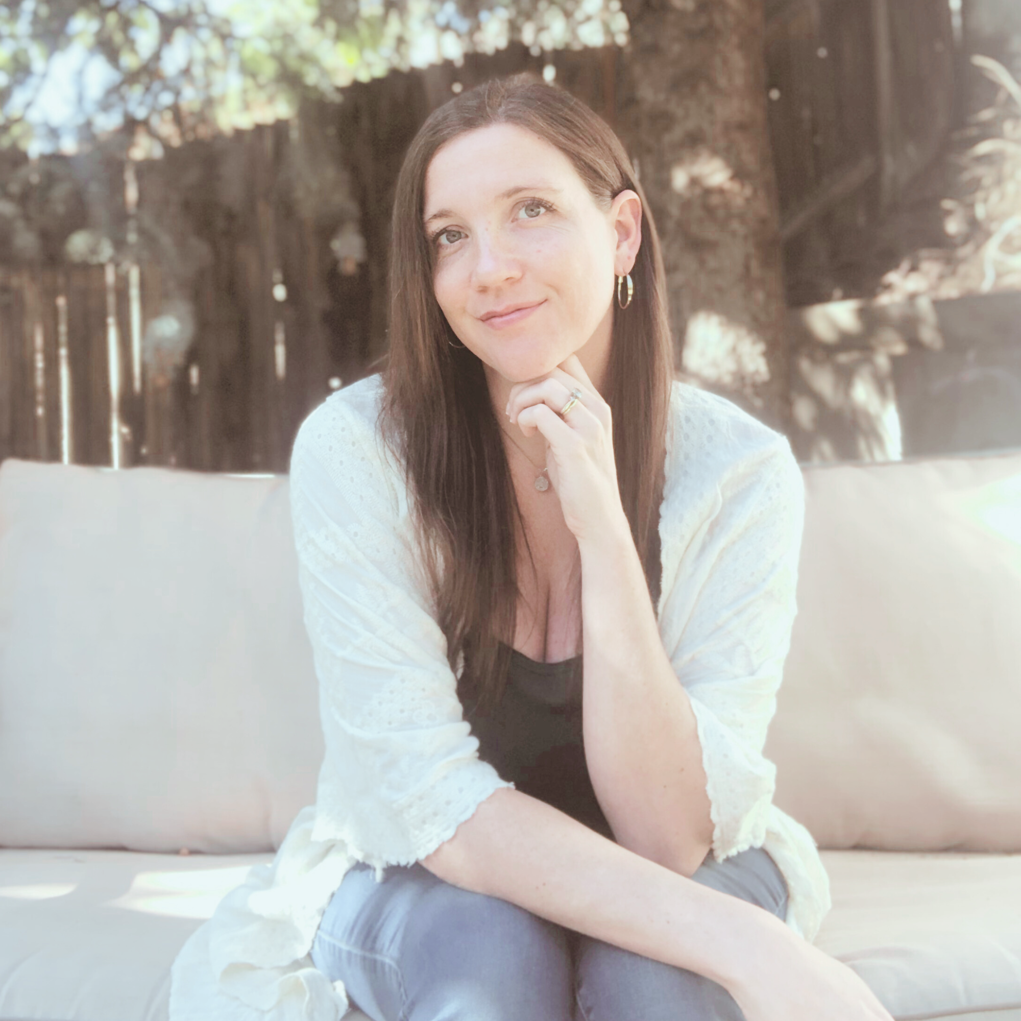 Colby Carr, Spiritual Life Coach and founder of Life of Oasis sitting on a sofa outside, resting her chin on her hand.