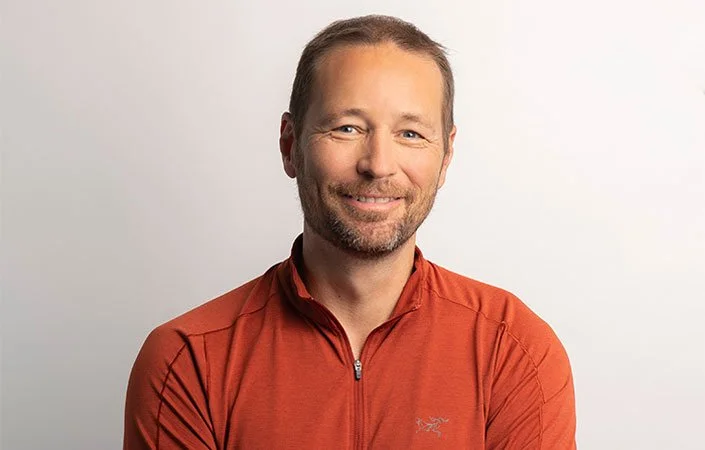 white male smiling in a orange sweater