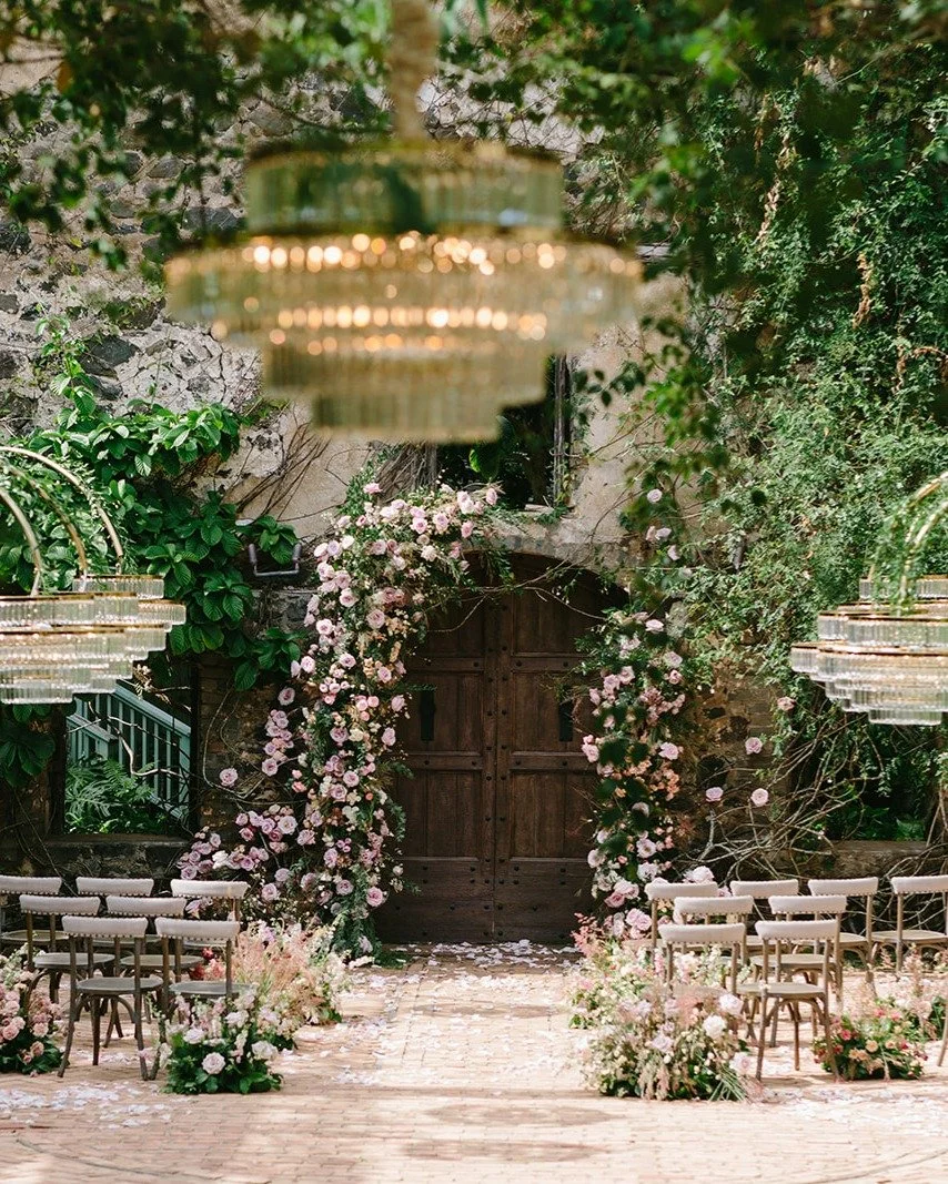 Dreaming back to Caitlin and Michael&rsquo;s wedding, this enchanting floral arch stole the show.

Soft blush roses spill gracefully around the doorway, intertwined with climbing greenery and set against weathered stone, creating a scene that feels b