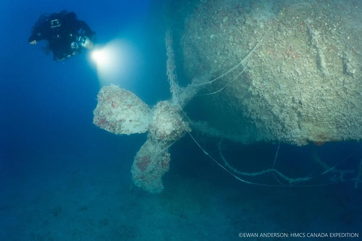 Diver Jason Cook illuminates the port-side propeller of HMCS Canada at 67 m (220 feet).