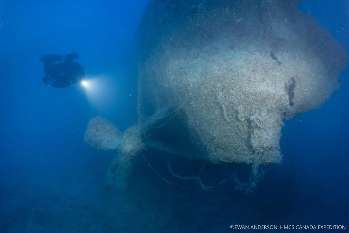 Diver Jason Cook illuminates the port-side propeller and stern of HMCS Canada at a depth of 67 m (220 feet).