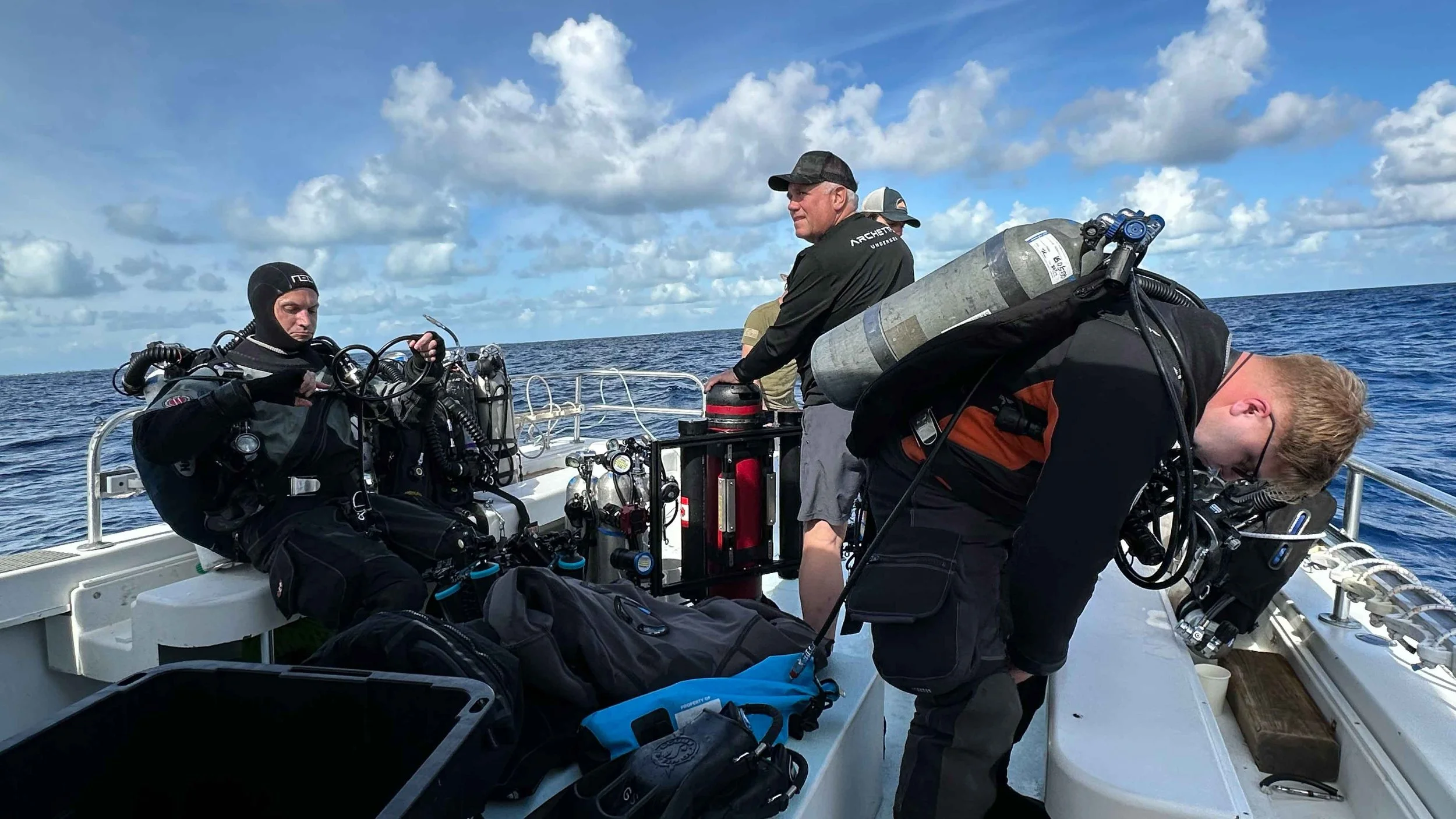 Ewan Anderson (left) and Jason Cook (right) prepare to dive while being assisted by Expedition Lead Diver Guy Shockey (centre).