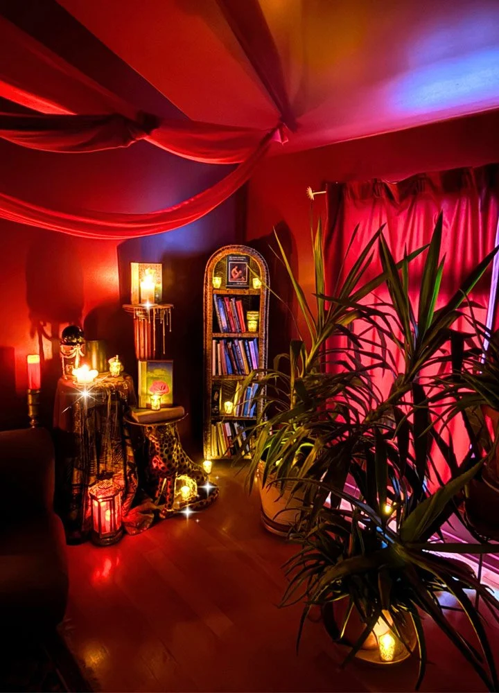 A cozy room decorated with red lighting, draped fabric ceiling, and string lights at Joytown, a transformational retreat & tantra sanctuary in Colorado.