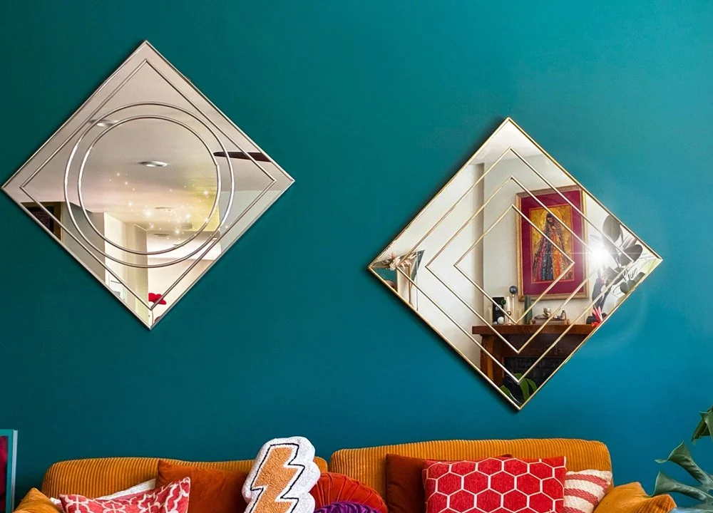 Decorative mirrors on a teal wall above a sofa with colorful pillows at Joytown, a transformational retreat & tantra sanctuary in Colorado.