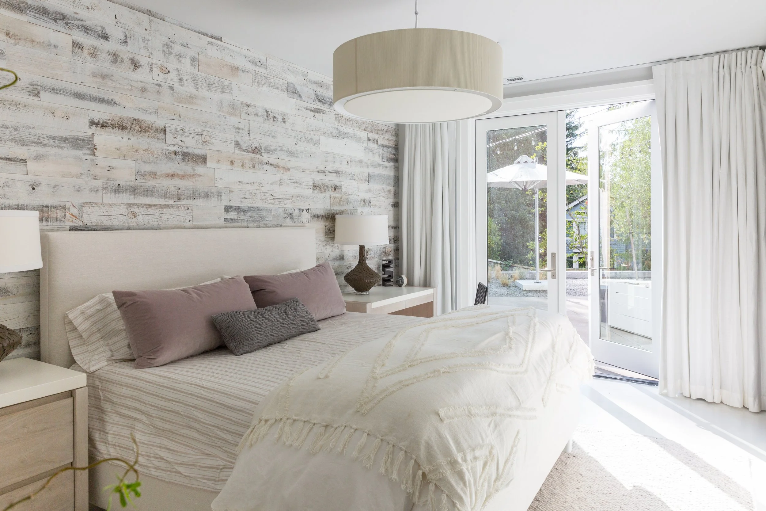 Serene and sophisticated, this luxury bedroom blends soft neutrals, rustic wood textures, and layered organic fabrics for a calming retreat that connects seamlessly to the outdoors. Designed for restorative living with a modern edge.