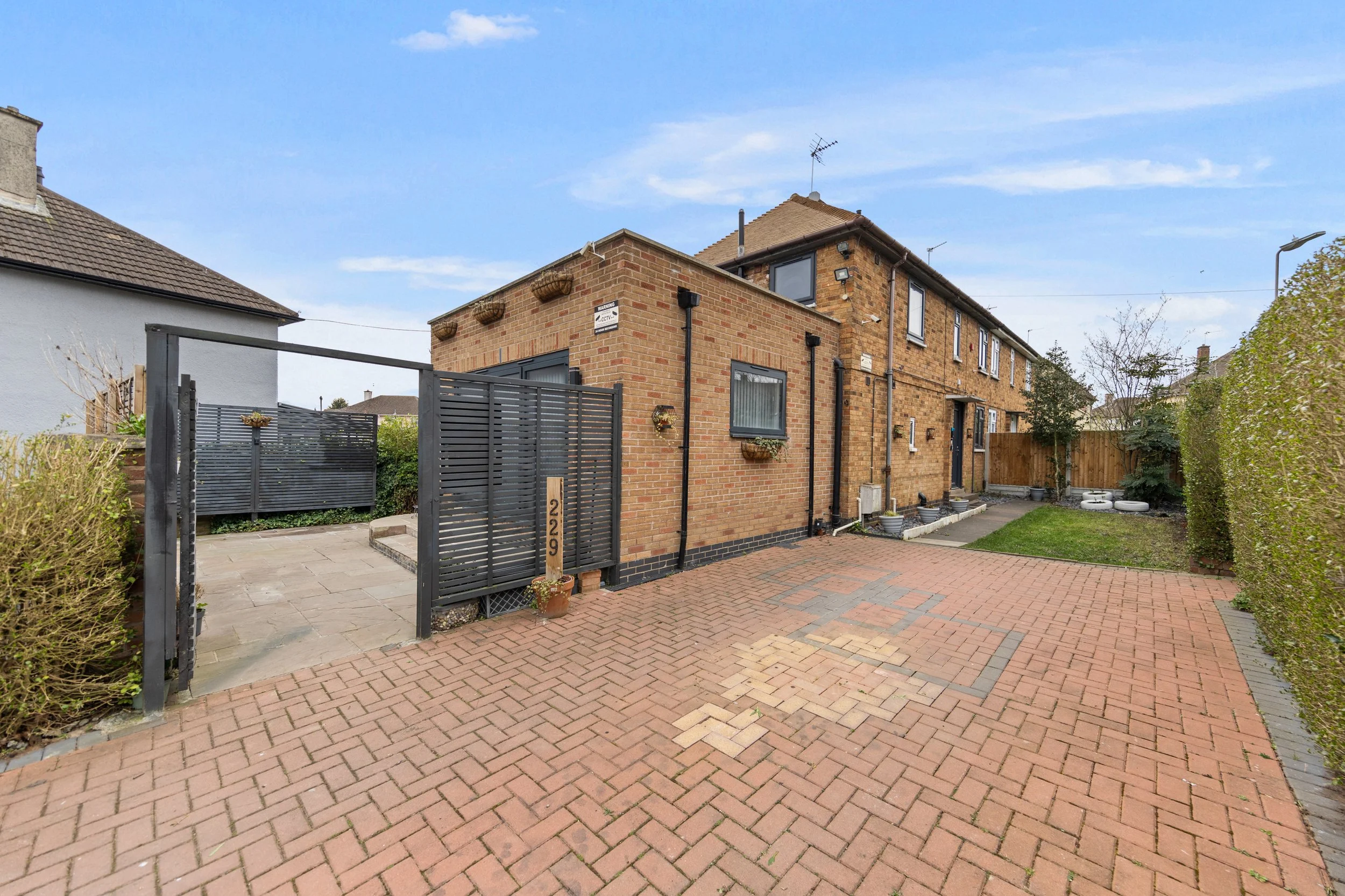 Front exterior of our New Parks accommodation in Leicester, with a large block-paved driveway for off-road parking and a gated side patio.