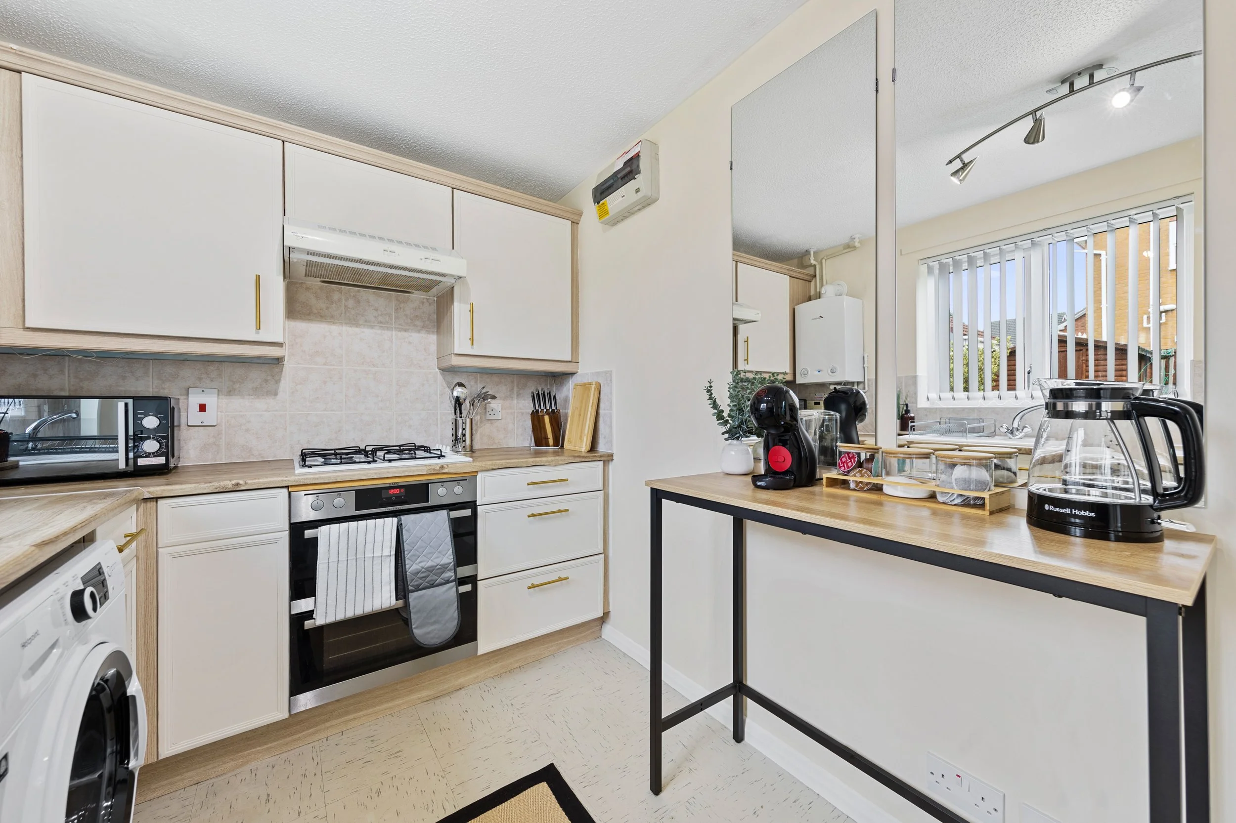 Fitted kitchen with oven, gas hob, washing machine and a breakfast bar with coffee machine at our Thorpe Astley accommodation in Leicester.