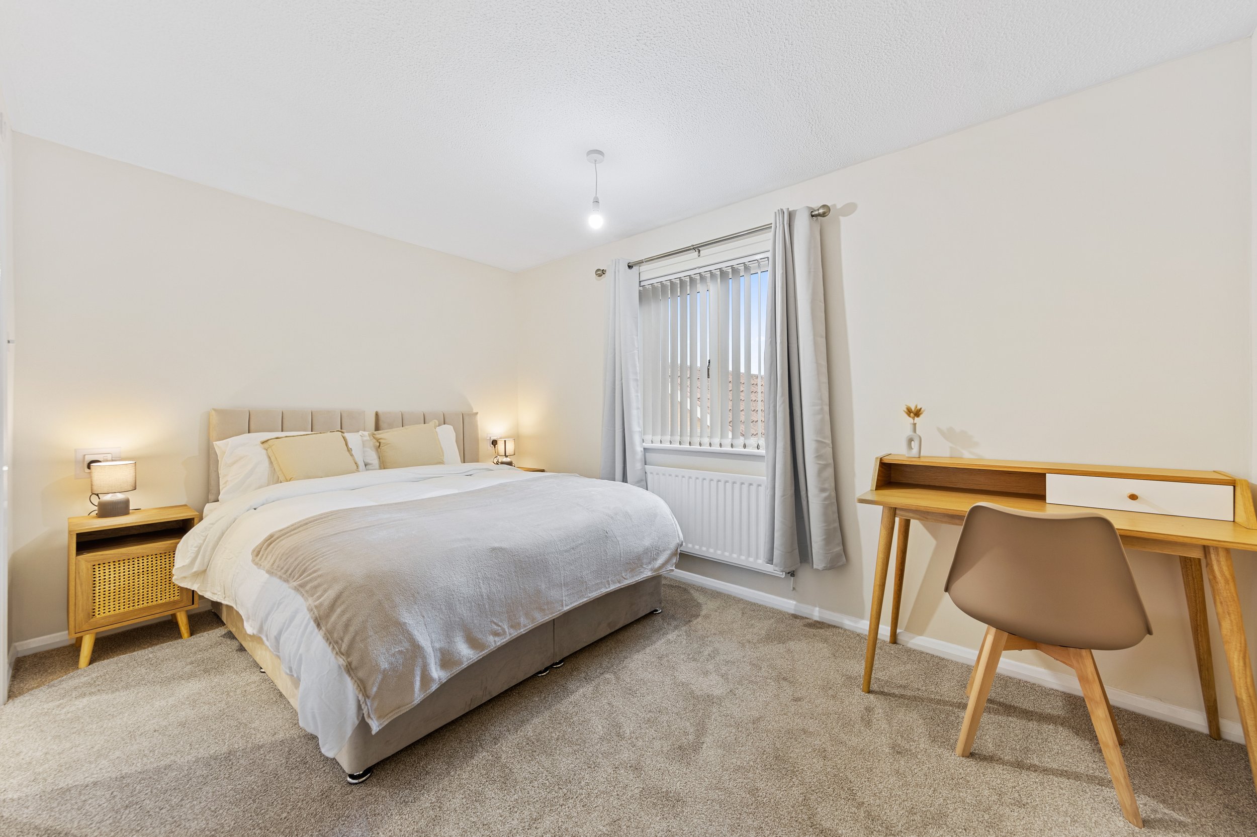 Double bedroom with upholstered bed, bedside lamps and a work desk at our Thorpe Astley accommodation in Leicester.