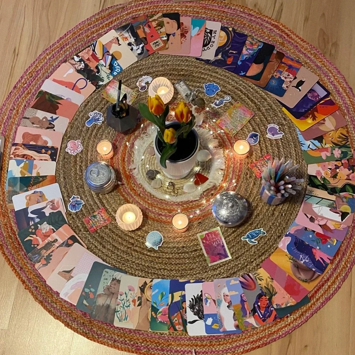 Ein runder Teppich, in der mitte stehen Tulpen, runherum liegen bunte Karten, Kerzen und Stifte