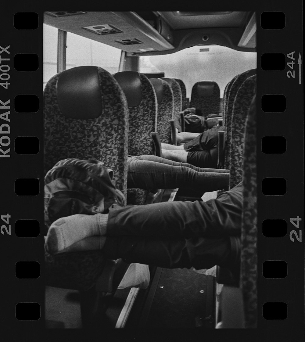 Interno di un autobus con alcune persone sedute, in bianco e nero.