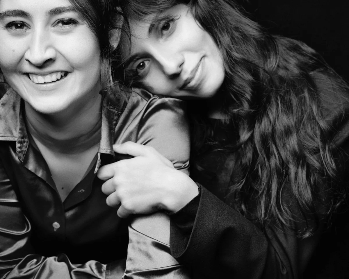 Due donne in primo piano, sorridenti, in un'immagine in bianco e nero.