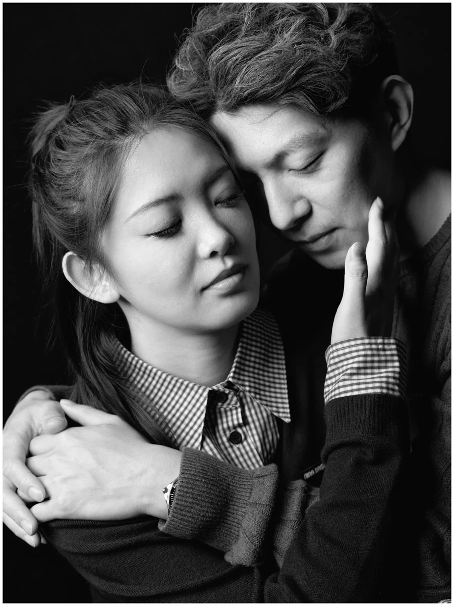 Due persone si abbracciano dolcemente, con occhi chiusi, in un'immagine in bianco e nero.