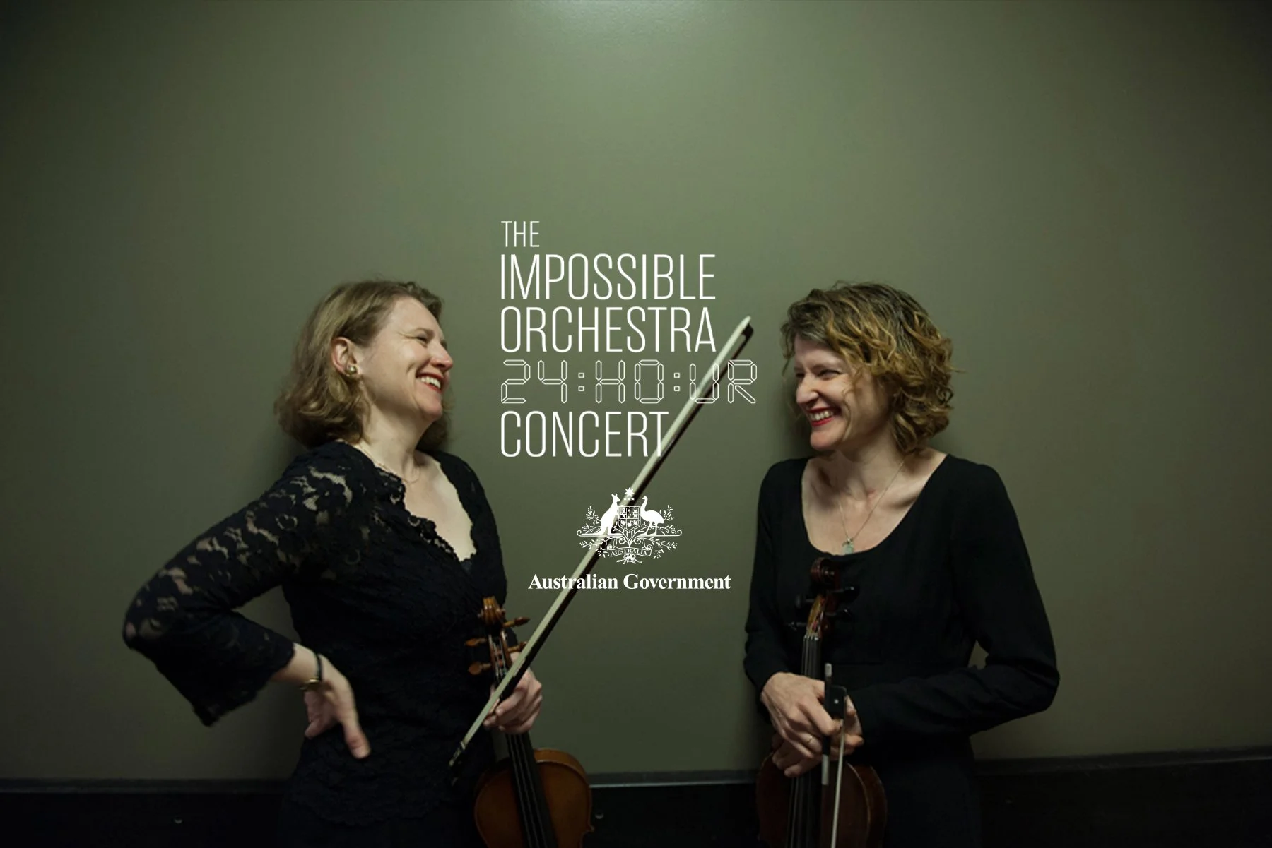 Pat Baron. Two women laughing and smiling while holding violins, standing in front of a plain green wall, with overlay text advertising a concert by The Impossible Orchestra, 24-hour event, hosted by the Australian Government.