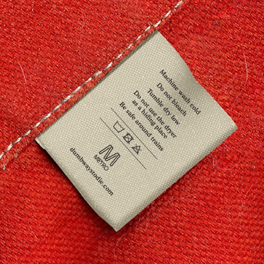 Clothing care label on red fabric indicating washing instructions and brand website.