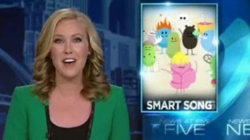 A female news anchor in a green blazer reporting on a segment titled 'Smart Song' featuring a colorful animated image of various cartoon monsters and characters.