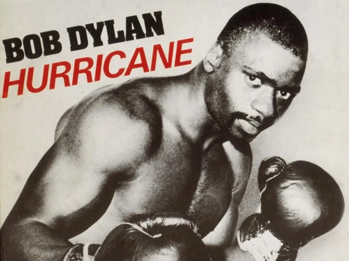 Close-up of a boxer holding gloves, with the text 'Bob Dylan Hurricane' in bold letters above. The image is in black and white.