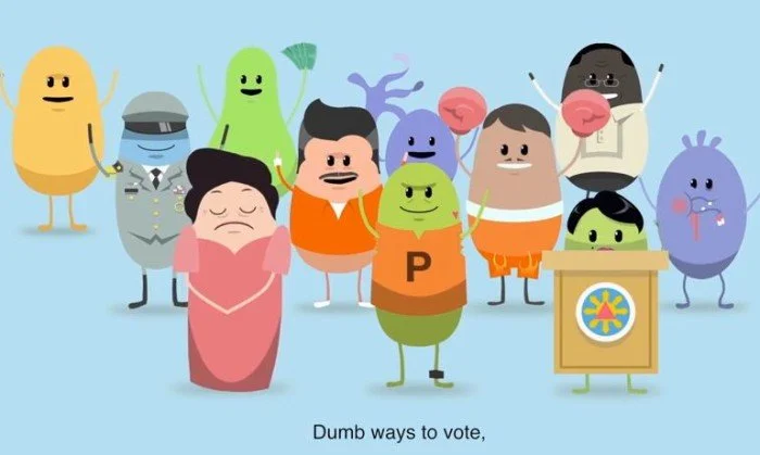 Cartoon characters of various colorful aliens and monsters gathered together, some behind a podium, with a woman in a pink dress in front. Caption reads, "Dumb ways to vote".