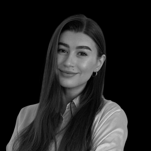 Black and white portrait of a young woman with long hair, smiling, wearing a collared shirt and hoop earrings.