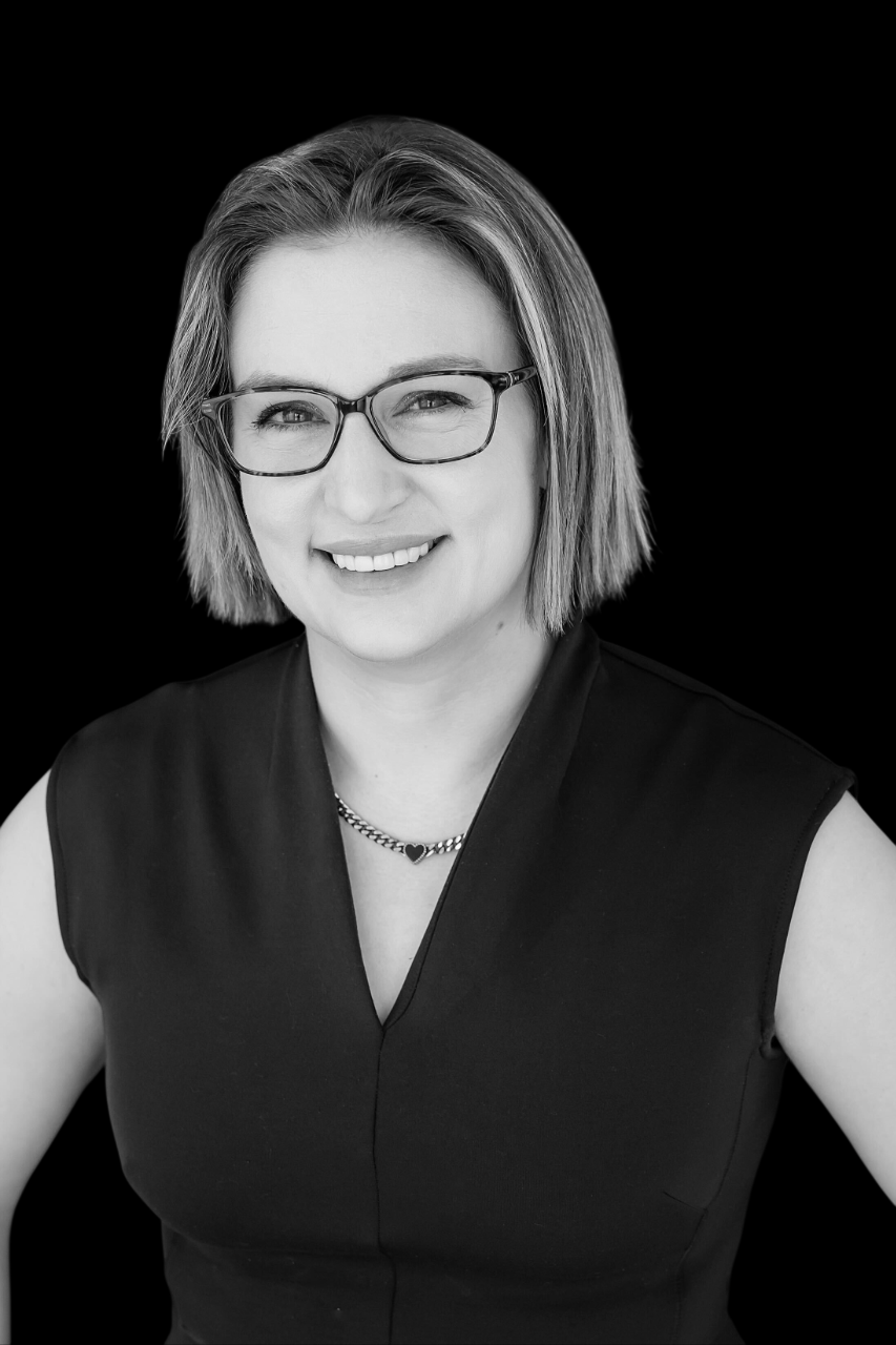 Black and white portrait of a smiling woman with shoulder-length hair against a dark background.
