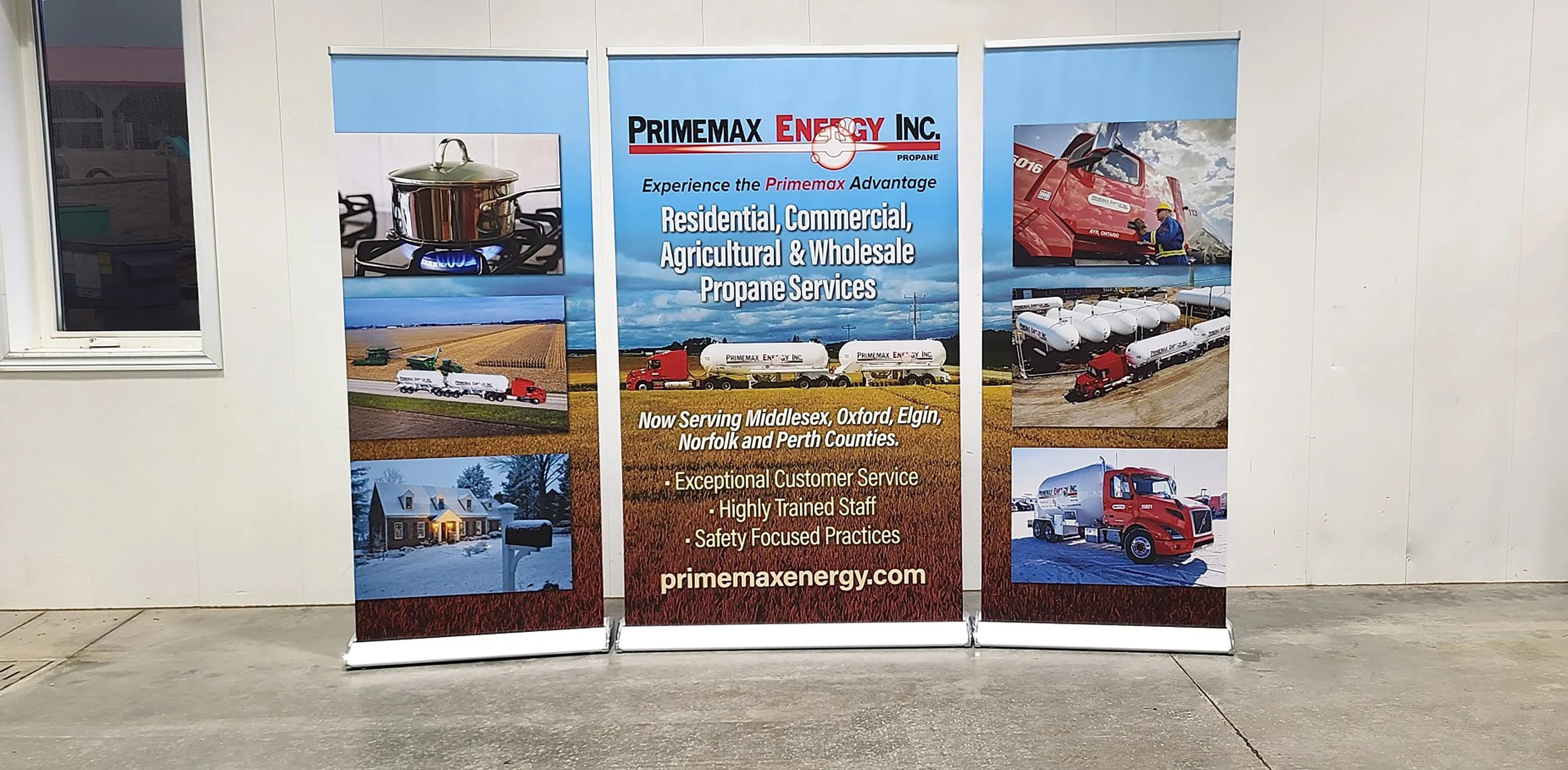 Three rolls of promotional banners for Primemax Energy Inc. showcasing propane services, with images of a stove, a home, trucks, and propane tanks.