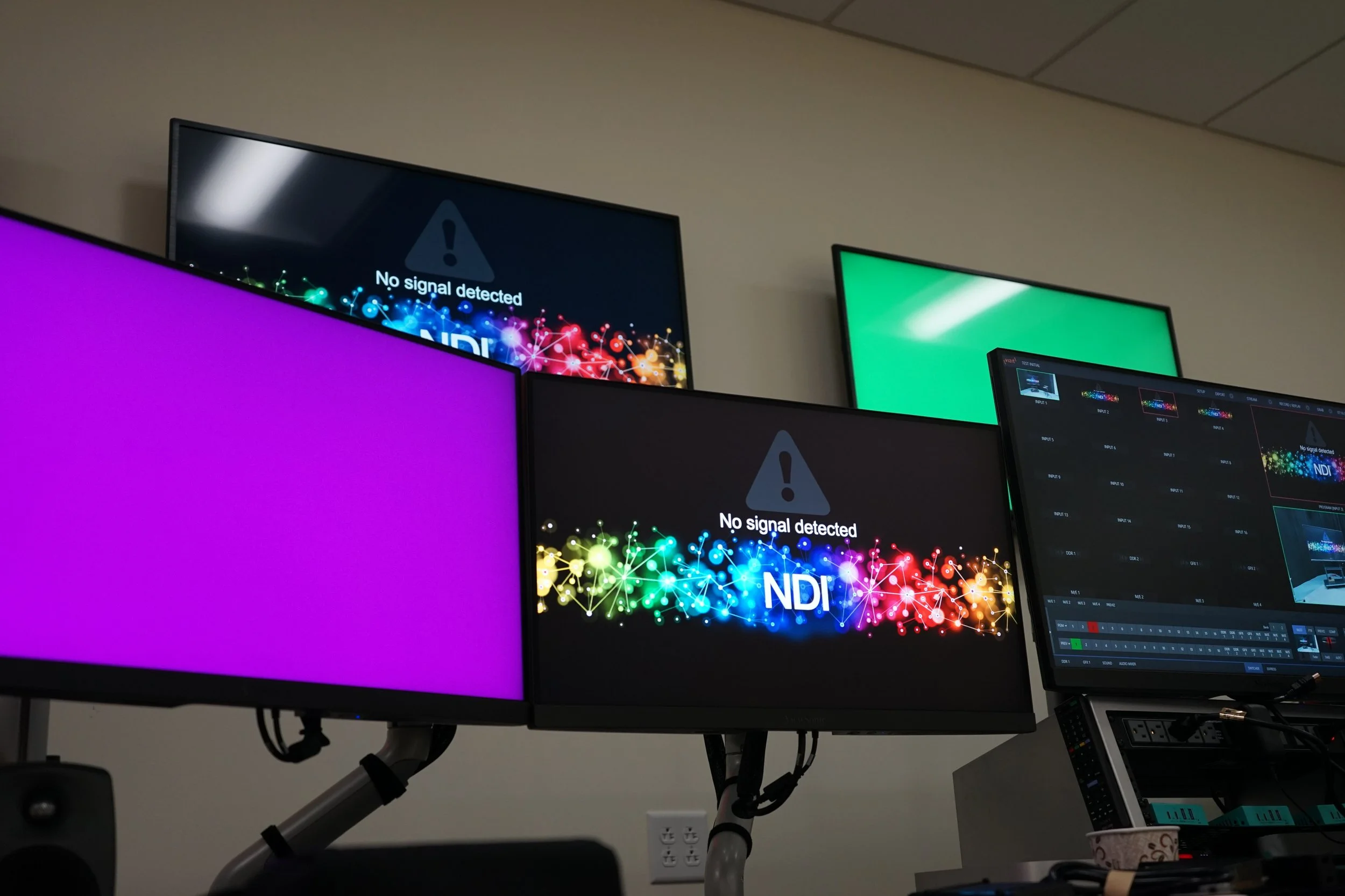 Modern video and audio production control room with multiple monitors, mixer, keyboards, speakers, and broadcast equipment.