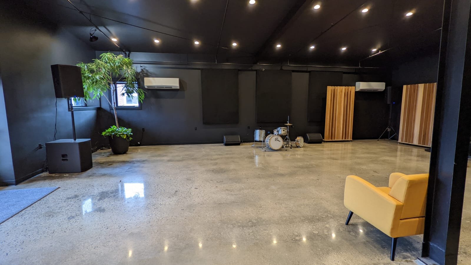 A music studio with a drum set, soundproofing panels, installed speakers and projectors. 