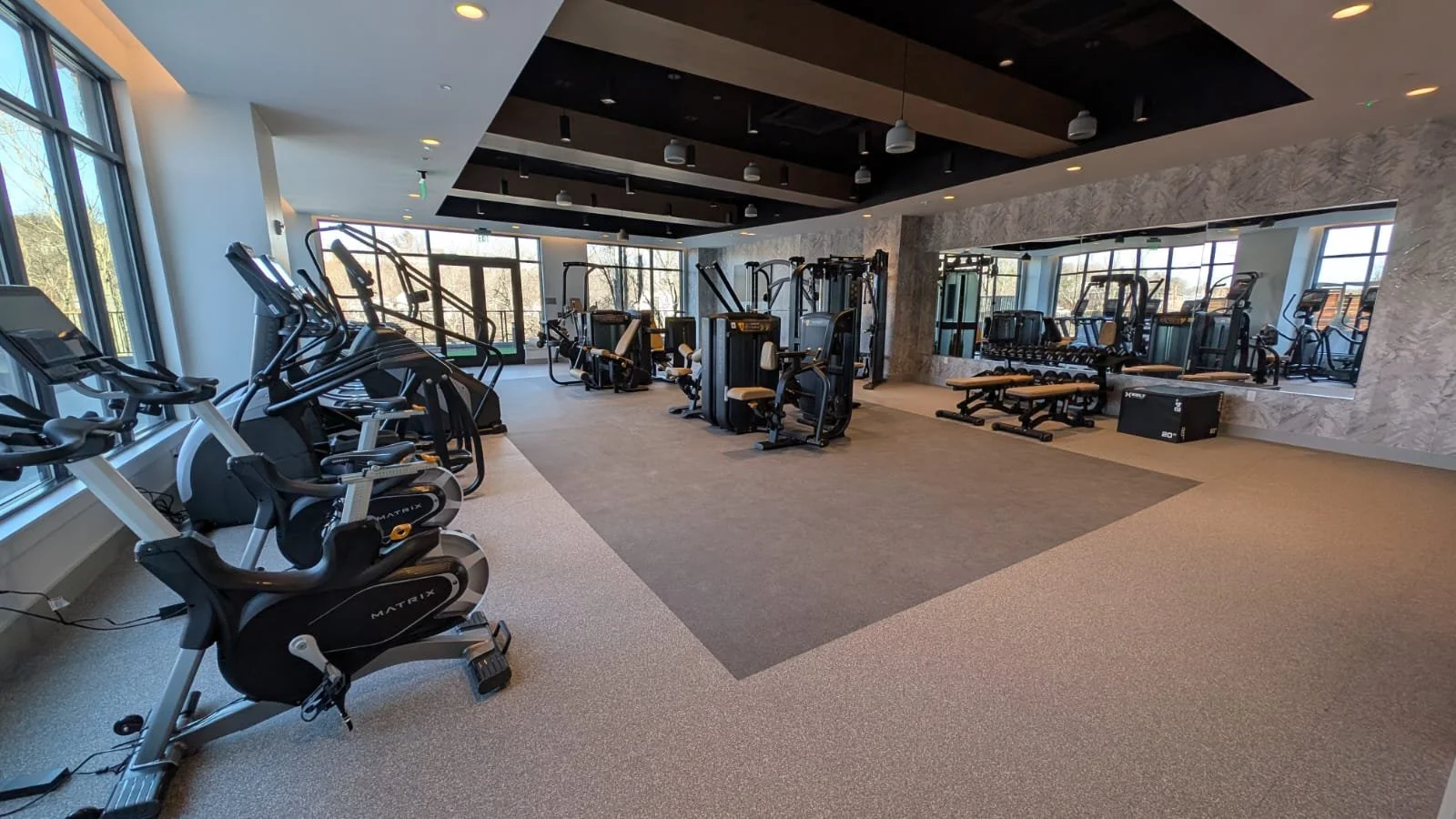 Modern gym with exercise bikes, weight machines, benches, and large mirrors.