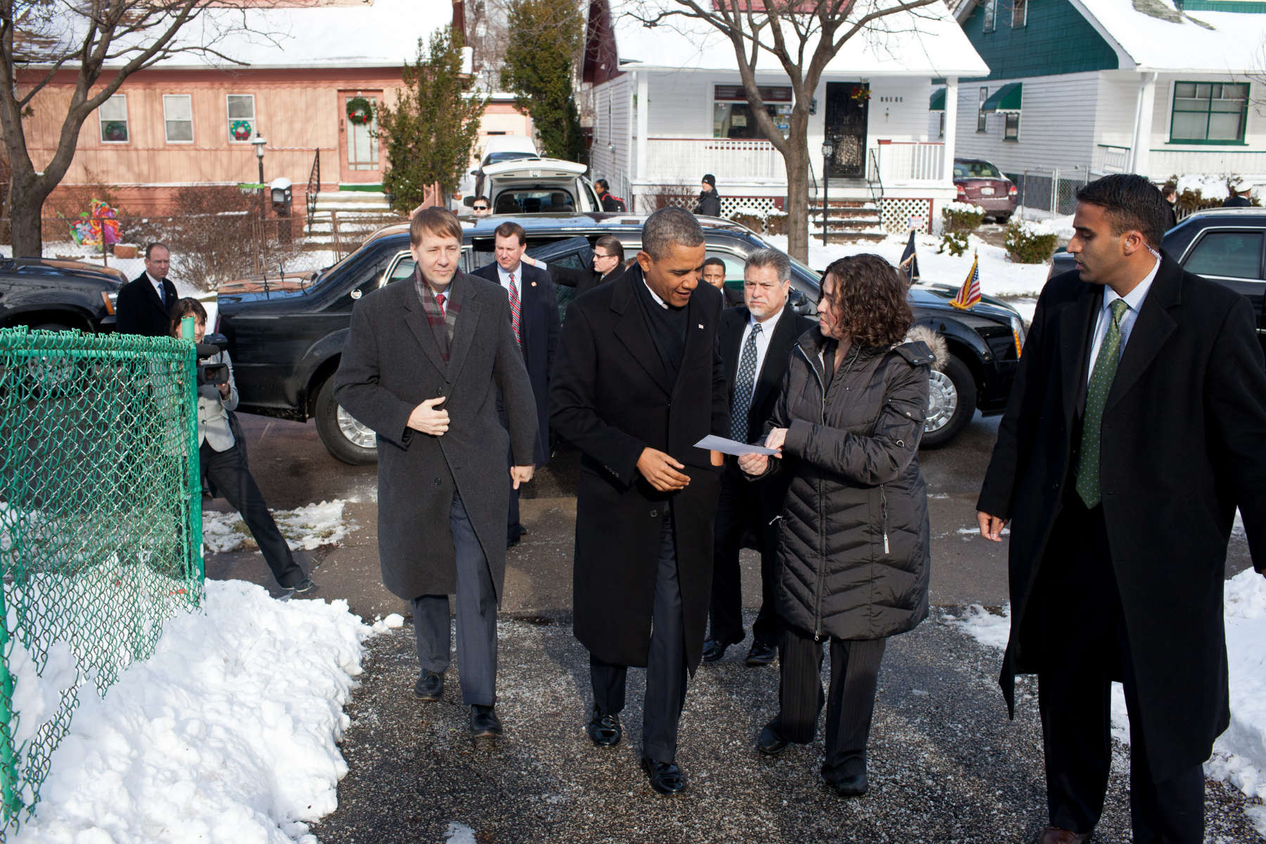 President Barack Obama walking with Lindsay Scola through a snowy neighborhood during an official visit.
