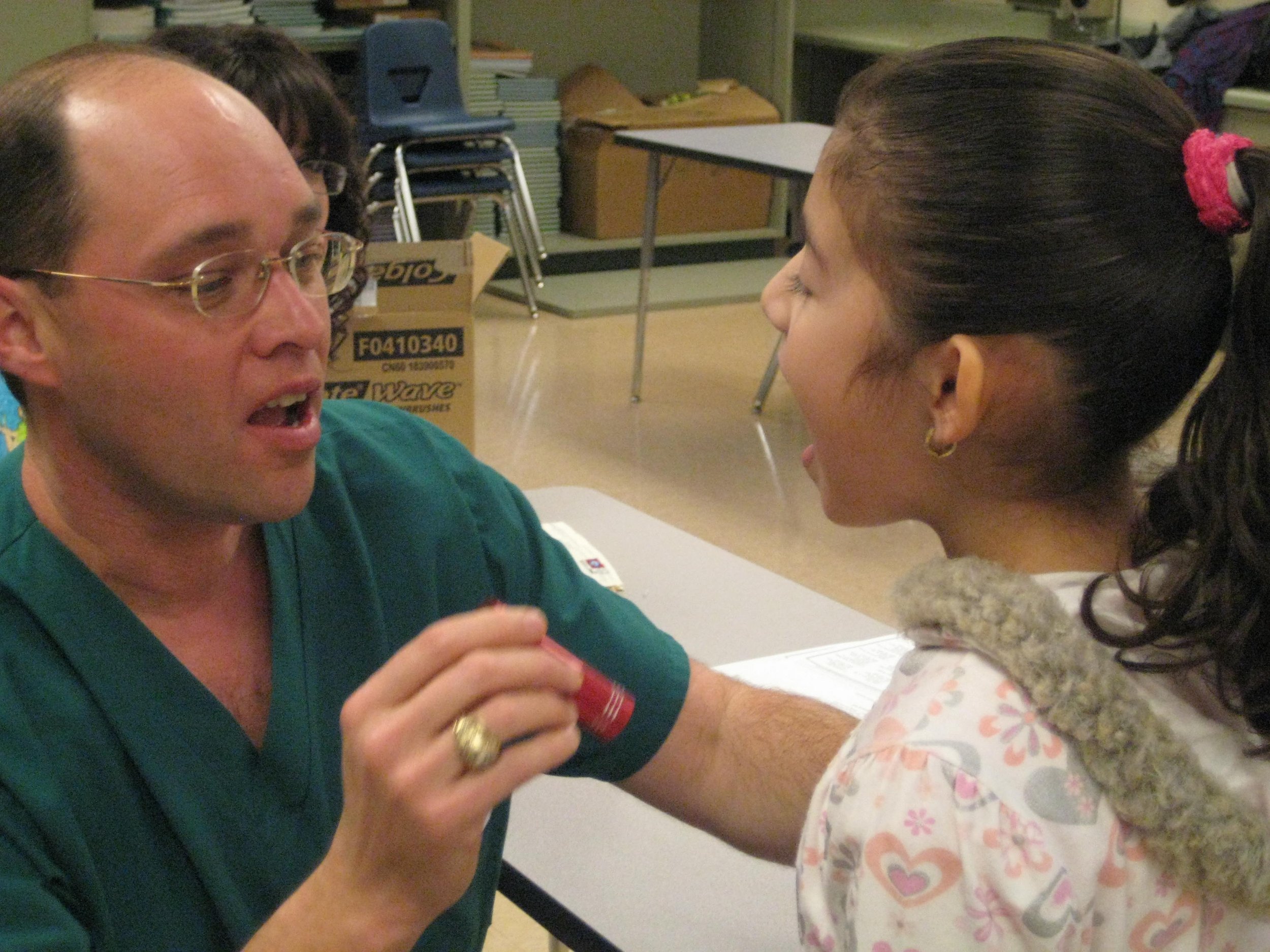 A male healthcare worker talking to a young girl in a medical setting.