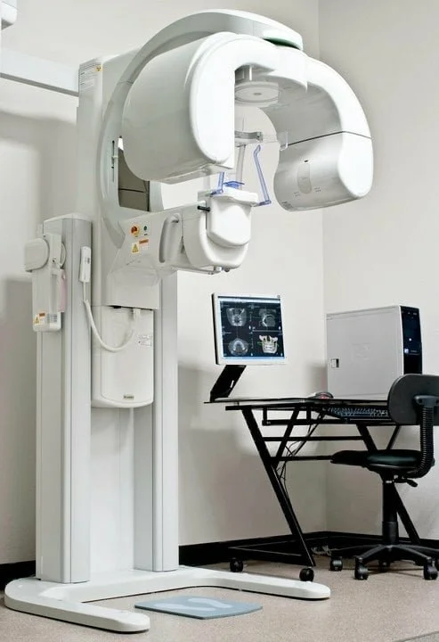 Medical imaging equipment, specifically a CT scanner, in a clinical setting with a computer workstation nearby.