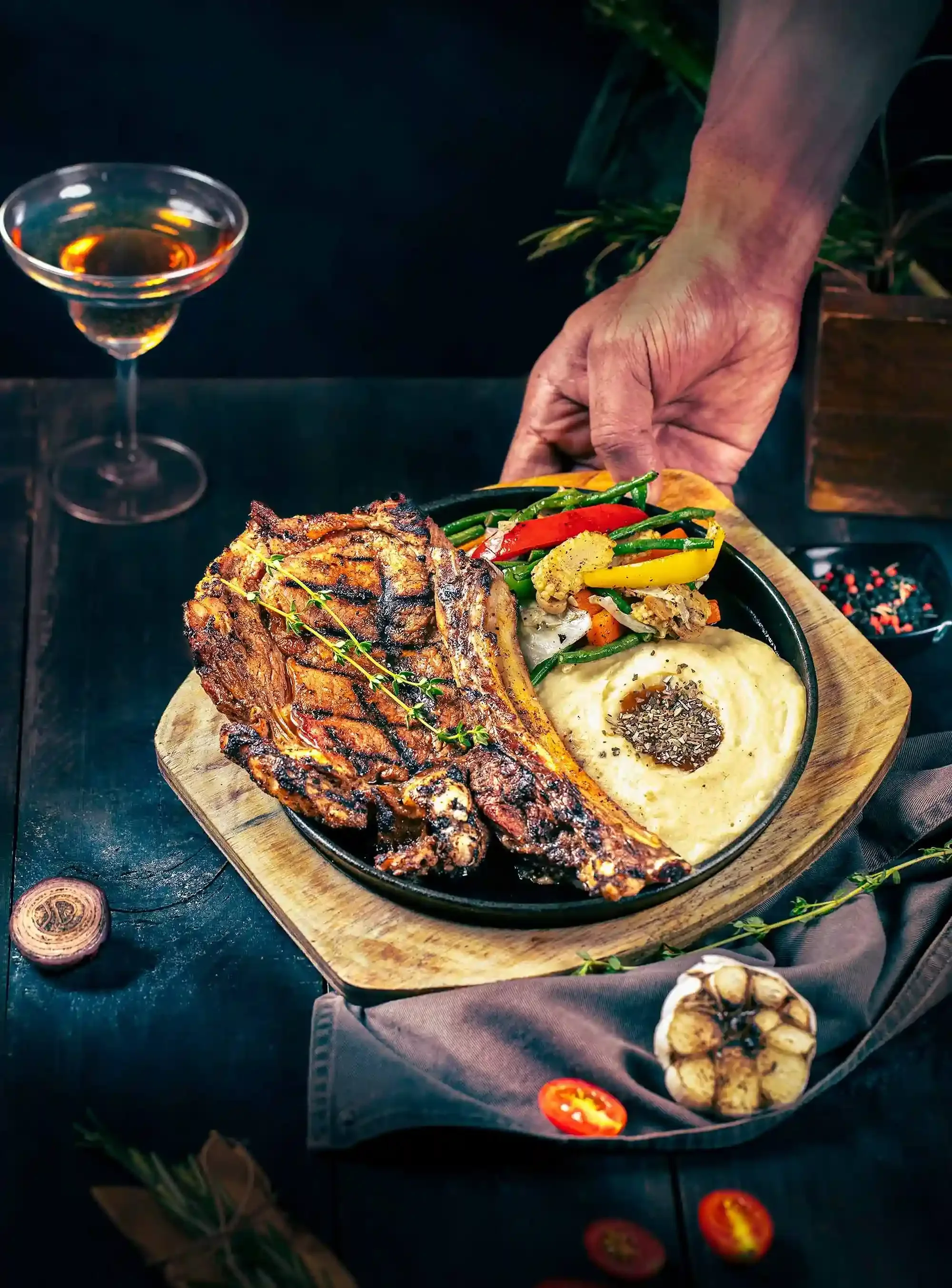 Top-down shot of a gourmet grilled steak platter with sides and a cocktail, showcasing the fine dining experience at Arrowhead Grill by Showmo Films.