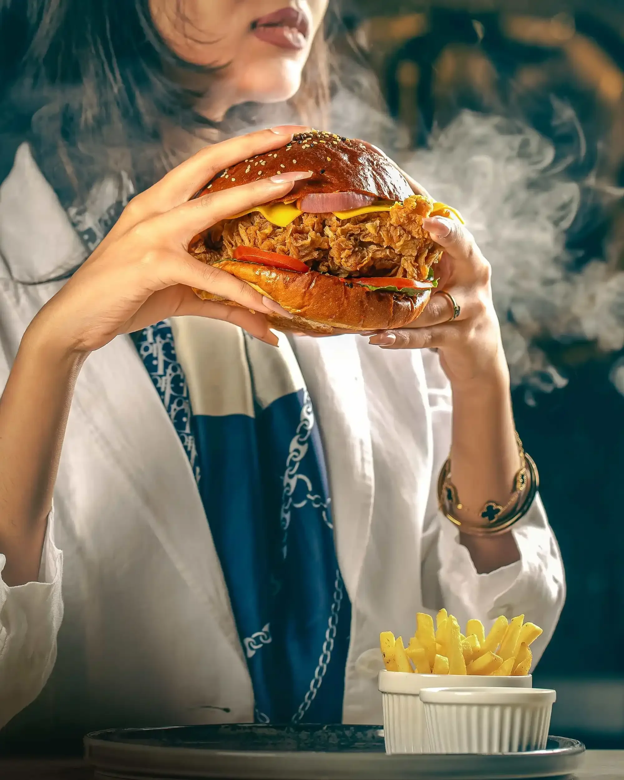 Commercial fast food photography of a model holding a steaming hot burger, highlighting appetizing textures and creative food styling for burger brands.