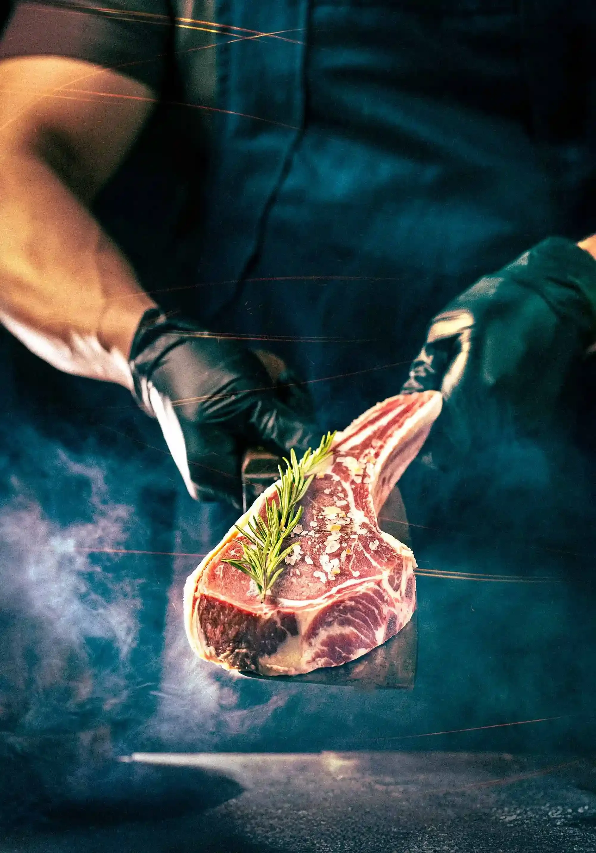 Cinematic food photography of a chef holding a raw tomahawk steak with a cleaver, highlighting premium meat quality and moody lighting for Arrowhead Grill.