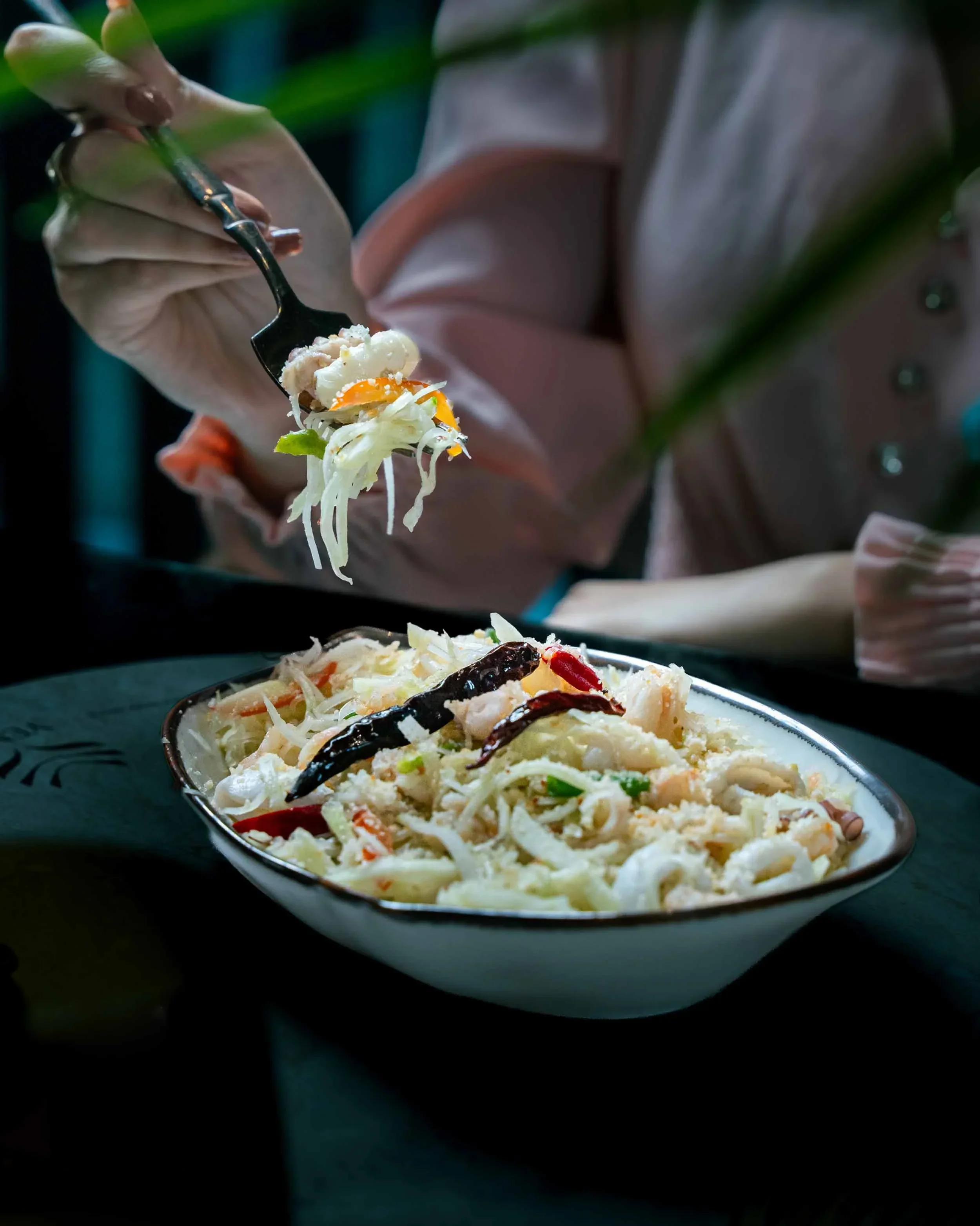 Close-up lifestyle shot of a diner enjoying an Asian fusion salad at Yenzo, capturing the restaurant's ambiance and culinary experience.