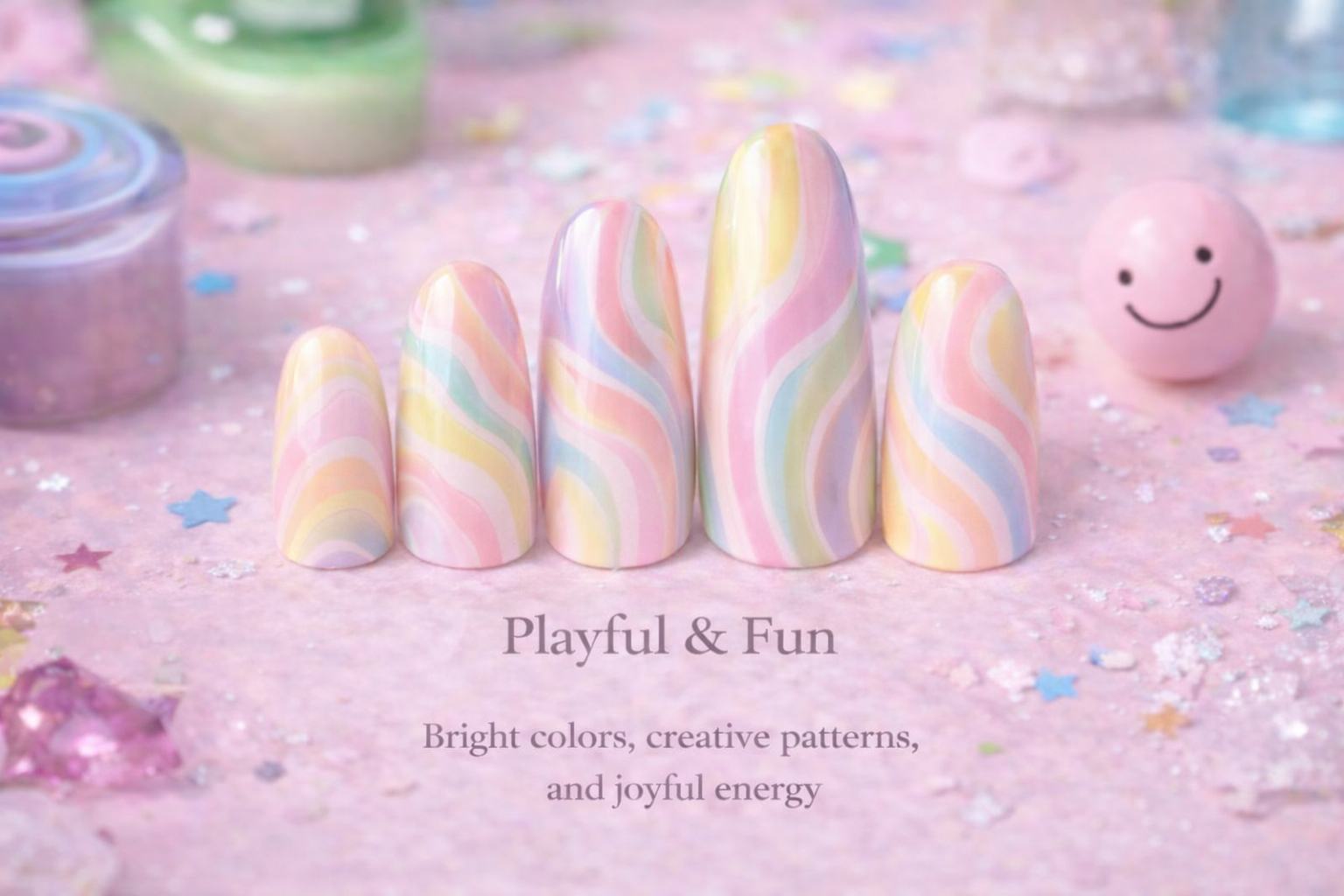 Colorful, pastel, rainbow-patterned artificial nails arranged in a row on a pink, glittery surface with confetti, a smiling pink ball, and small containers of glitter in the background.