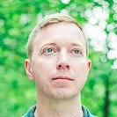 Portrait of a man outdoors with green foliage background.