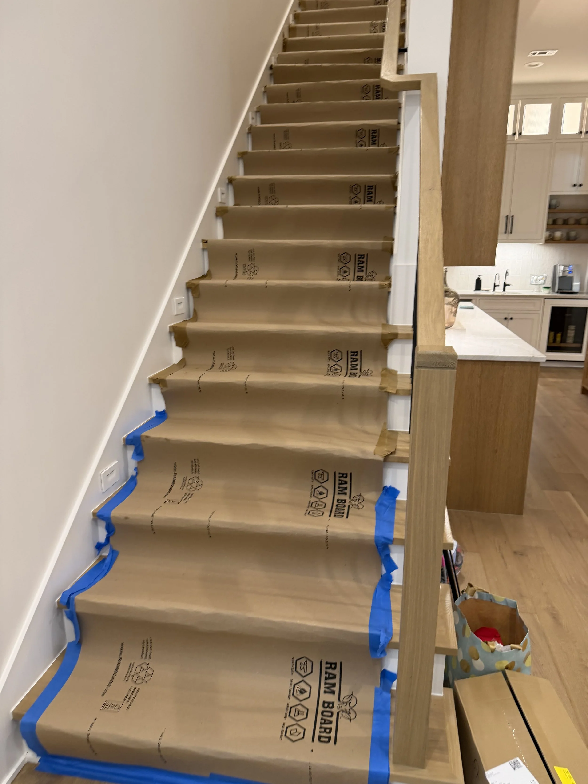 Hardwood staircase protected with Ram Board before moving a Peloton Tread Plus upstairs in a Houston home